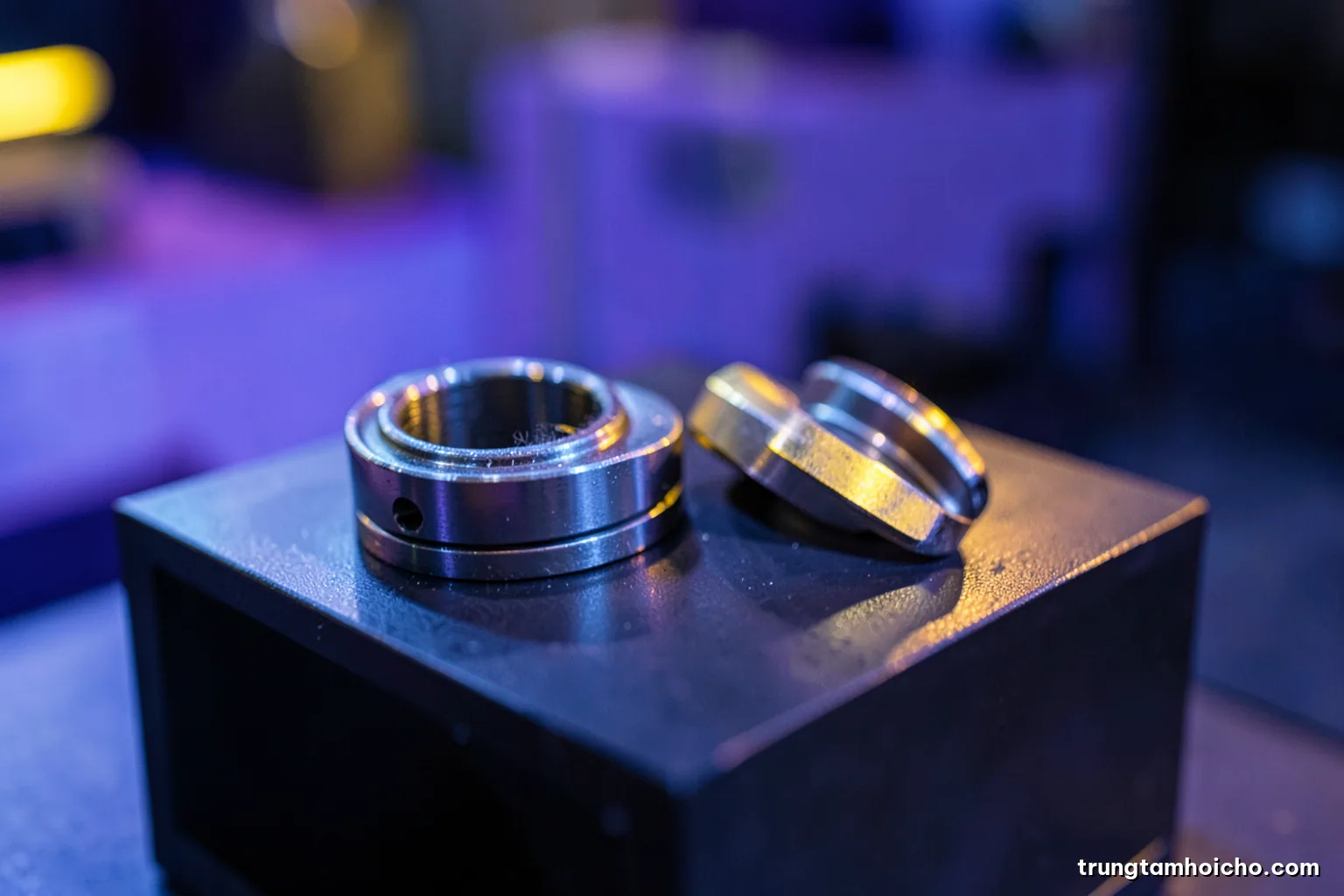 Macro close-up of precision machined metal parts on a dark display stand under focused cool light, shallow depth of field, steel blue and graphite palette, industrial editorial photography