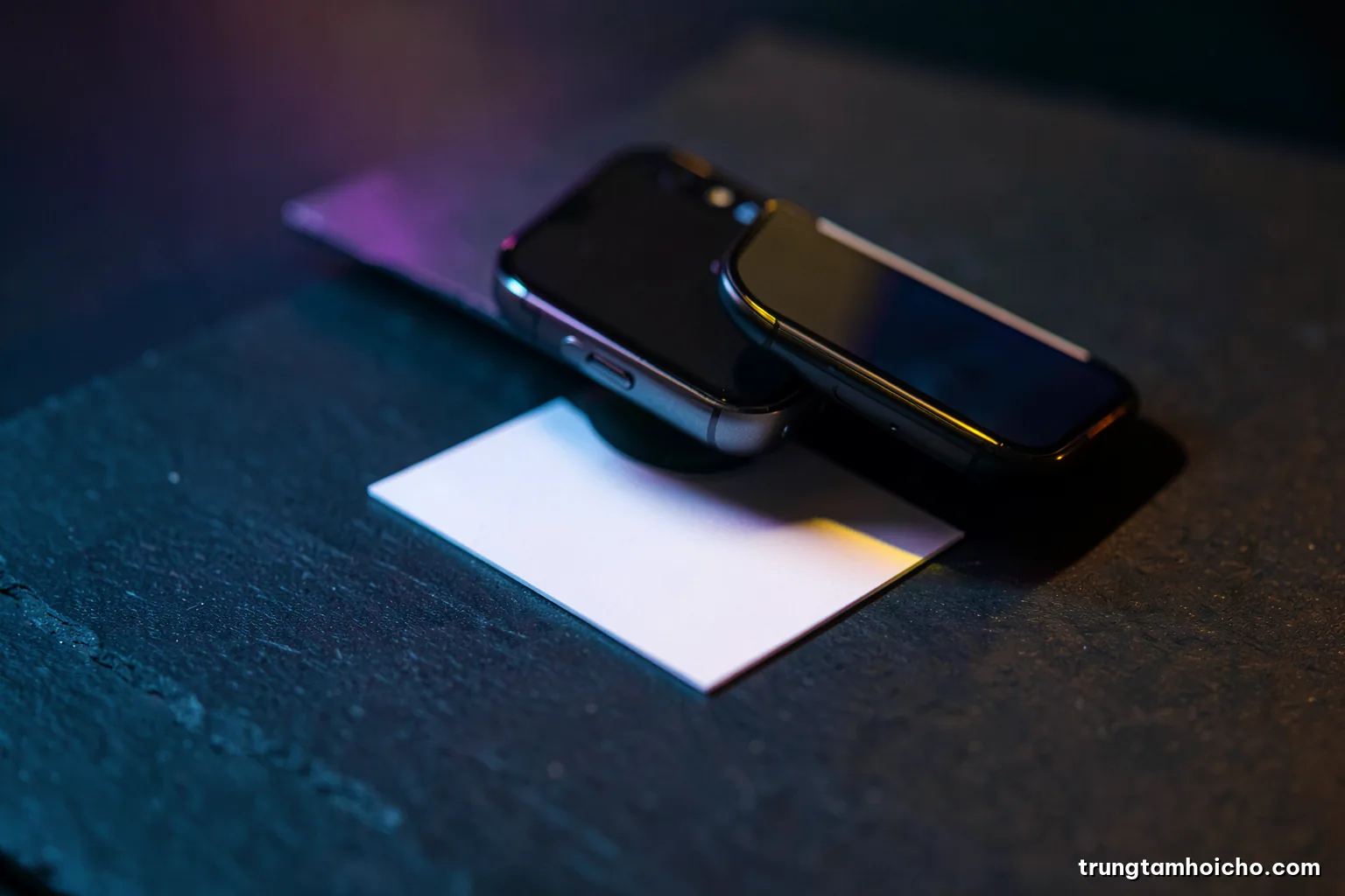 Macro shot of a smartphone camera hovering over a blank business card on a dark slate surface, cool side light, deep teal and silver palette, minimalist composition